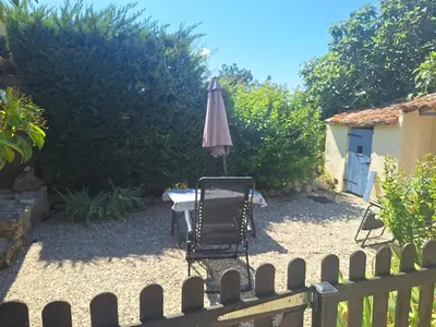 a table with an umbrella and a chair in a yard at Le Portail Vert in Villes-sur-Auzon