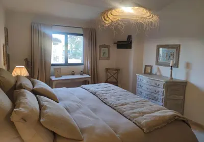 a bedroom with a large bed with a dresser and a window at Le Mas Natán in Gordes