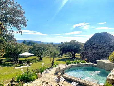 a swimming pool in a yard with a rock house at Le Mas Natán in Gordes