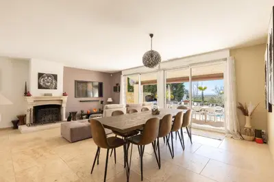 a dining room with a table and chairs and a couch at La Villa L'Isle-St-Antoine piscine chauffée in LʼIsle-sur-la-Sorgue