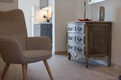 a living room with a chair and a dresser at La Villa L'Isle-St-Antoine piscine chauffée in LʼIsle-sur-la-Sorgue