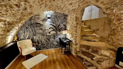 a room with a stone wall with a staircase and a desk at Suite dans le centre historique in Aix-en-Provence