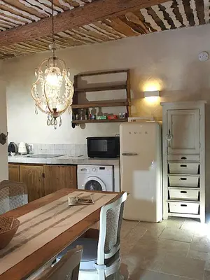 a kitchen with a table and a white refrigerator at Le LOFT LOURMARIN in Lourmarin