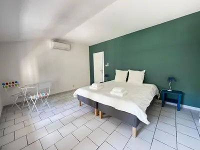 a bedroom with a large bed and a green wall at La Provençale - Piscine - Chambres climatisées in Aubignan