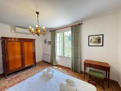 a bedroom with a bed and a desk and a window at La Provençale - Piscine - Chambres climatisées in Aubignan
