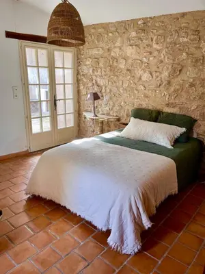 a bedroom with a bed and a stone wall at Charmante maison de village dans le Luberon in Beaumont-de-Pertuis