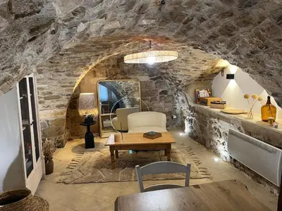 a living room with a table and a stone wall at Charmante maison de village dans le Luberon in Beaumont-de-Pertuis