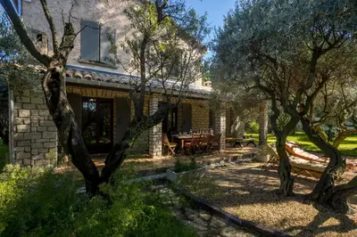 a stone house with a patio and trees at Gite Lucie in Carpentras