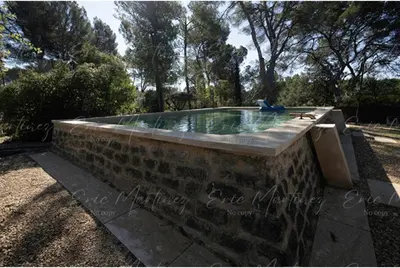 a stone wall around a swimming pool in a yard at Gite Lucie in Carpentras