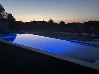 a swimming pool with blue water at sunset at Villa Noyau & Pépin in Rognes