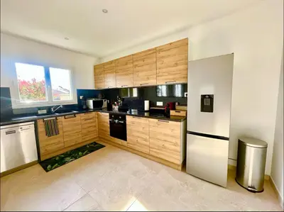 a kitchen with wooden cabinets and a stainless steel refrigerator at Évasion Ventoux, villa spacieuse et accessible PMR in Carpentras