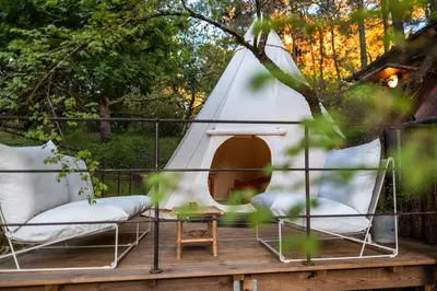 a tent on a deck with two chairs and a table at Tipi à Roussillon in Roussillon