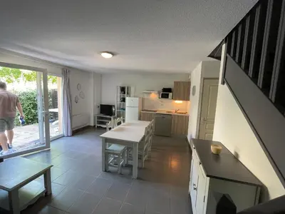 a living room with a staircase and a kitchen with a table at Maison aux Demeures du Ventoux in Aubignan