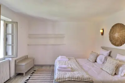 a white bedroom with a bed and a window at L’oustaou de Ventabren Village Square in Ventabren