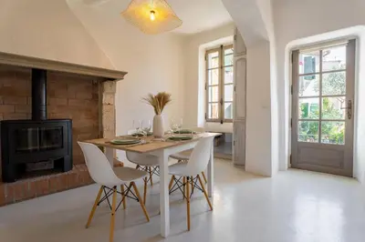 a dining room with a table and chairs and a fireplace at L’oustaou de Ventabren Village Square in Ventabren
