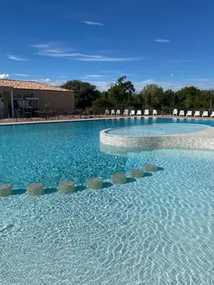 a large swimming pool with chairs and blue water at Maison aux Demeures du Ventoux Adaptée PMR in Aubignan