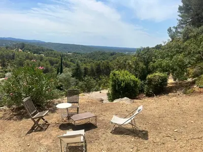 a table and chairs under an umbrella in a yard at Aix-en-Provence, Bastidon provençal plein cœur de la forêt avec vue unique in Le Tholonet