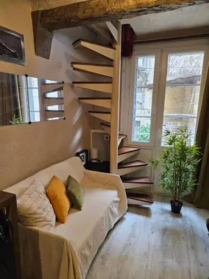 a living room with a couch and a spiral staircase at T2 charmant avec mezzanine au cœur d'Aix in Aix-en-Provence