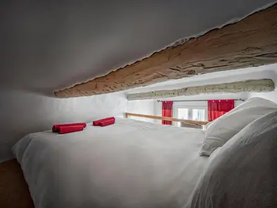 a white bed with two red pillows on top of it at T2 charmant avec mezzanine au cœur d'Aix in Aix-en-Provence