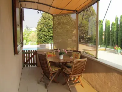 a patio with a table and chairs on a porch at Maison en PROVENCE in Robion en Luberon