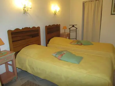 a bedroom with two beds and a table with a lamp at Maison en PROVENCE in Robion en Luberon