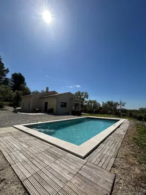 a swimming pool with a wooden deck next to a house at Charmante maison avec piscine et grand jardin in LʼIsle-sur-la-Sorgue