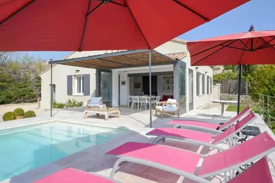 a group of chairs and umbrellas next to a pool at Villa Cali - Air-conditioned, Pool, Heart Village in Cabrières-dʼAvignon