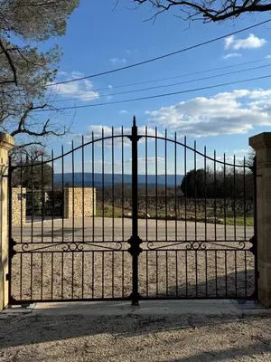 an iron gate with a view of a field at Le Mazet de la Truffière in Gordes