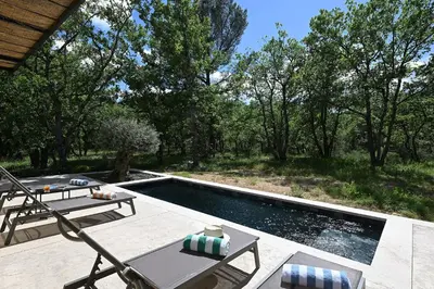 a swimming pool with a picnic table and chairs next to it at Le Mazet de la Truffière in Gordes