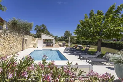 a swimming pool in a yard with chairs and trees at Villa Vue Luberon in Gordes