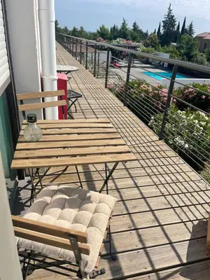 a wooden bench sitting on a balcony next to a pool at Studio cosy, résidence de tourisme avec piscine in Aix-en-Provence