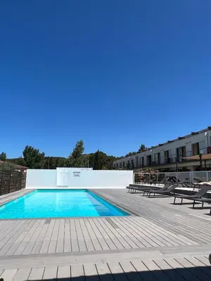 a swimming pool with two benches and a building at Studio cosy, résidence de tourisme avec piscine in Aix-en-Provence