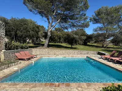 a swimming pool with two chairs and a tree at Mas traditionnel à Gordes en pleine nature in Gordes