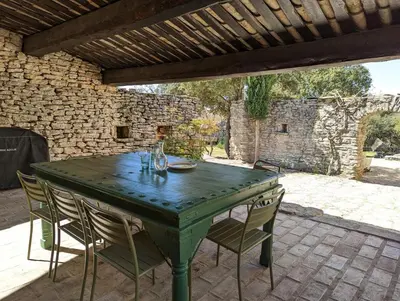 a green table and chairs on a patio at Mas traditionnel à Gordes en pleine nature in Gordes
