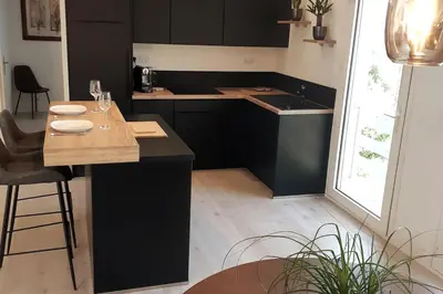 a kitchen with black cabinets and a table with chairs at Appartement Aix, résidence calme avec piscine in Aix-en-Provence