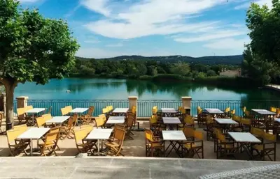 a group of tables and chairs in front of a lake at SUNRISE - Golf de Pont Royal in Mallemort