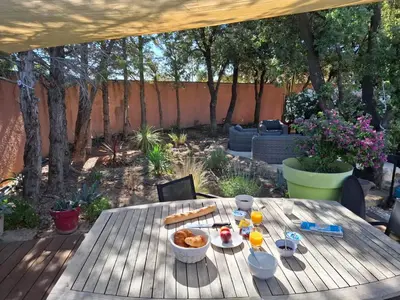 a wooden table with food and drinks on a patio at Logement indépendant avec Jacuzi pour 4ou 5 personnes, 2 chambres in Aureille