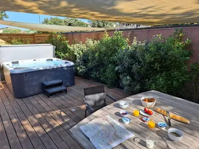 a hot tub on a wooden deck with a table and a table at Logement indépendant avec Jacuzi pour 4ou 5 personnes, 2 chambres in Aureille
