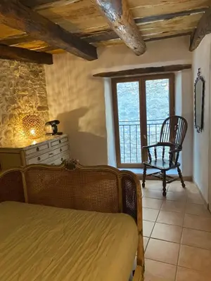 a bedroom with a bed and a chair and a window at Room in Medieval Cereste in Céreste