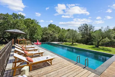 a pool with chairs and an umbrella next to a wooden deck at Big Modern Villa Ste Victoire 10min CityCenter Aix in Saint-Marc-Jaumegarde