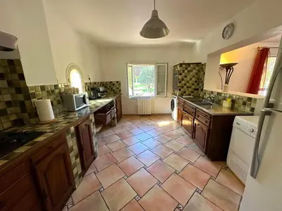 a kitchen with a tiled floor with a sink and a refrigerator at Le Mas des lys - Guest houses au coeur de la Provence dans un parc paysagé avec piscine, sauna et boulodrome in Grans