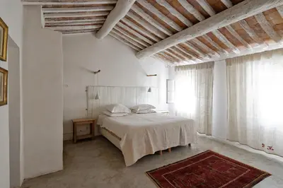 a white bedroom with a bed and a large window at La Grande Bastide in Vaugines