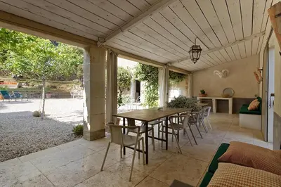a patio with a wooden table and chairs at La Grande Bastide in Vaugines