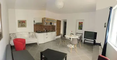 a kitchen and living room with a couch and a tv at GitesLuberon 2 F2 in Charleval
