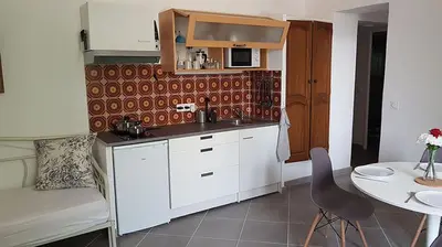 a kitchen with white cabinets and a table and a chair at GitesLuberon 2 F2 in Charleval
