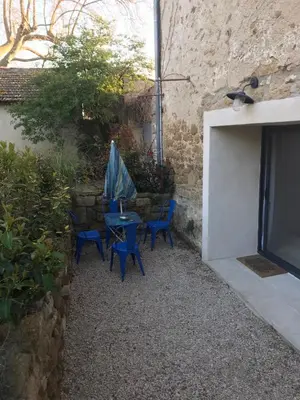 a patio with blue chairs and a table in a courtyard at Studio indépendant avec piscine proche Lourmarin in Lourmarin