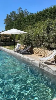 two chairs and an umbrella next to a swimming pool at Studio indépendant avec piscine proche Lourmarin in Lourmarin