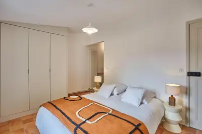 a white bedroom with a large bed with a brown blanket at Bastide entièrement rénovée au coeur de Goult in Goult