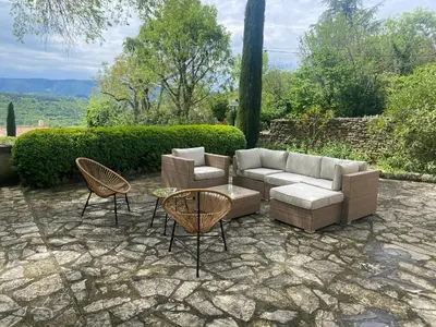 a patio with a couch and two chairs and a table at Bastide entièrement rénovée au coeur de Goult in Goult