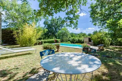 a table and chairs in a yard with a pool at Maison de James in Murs